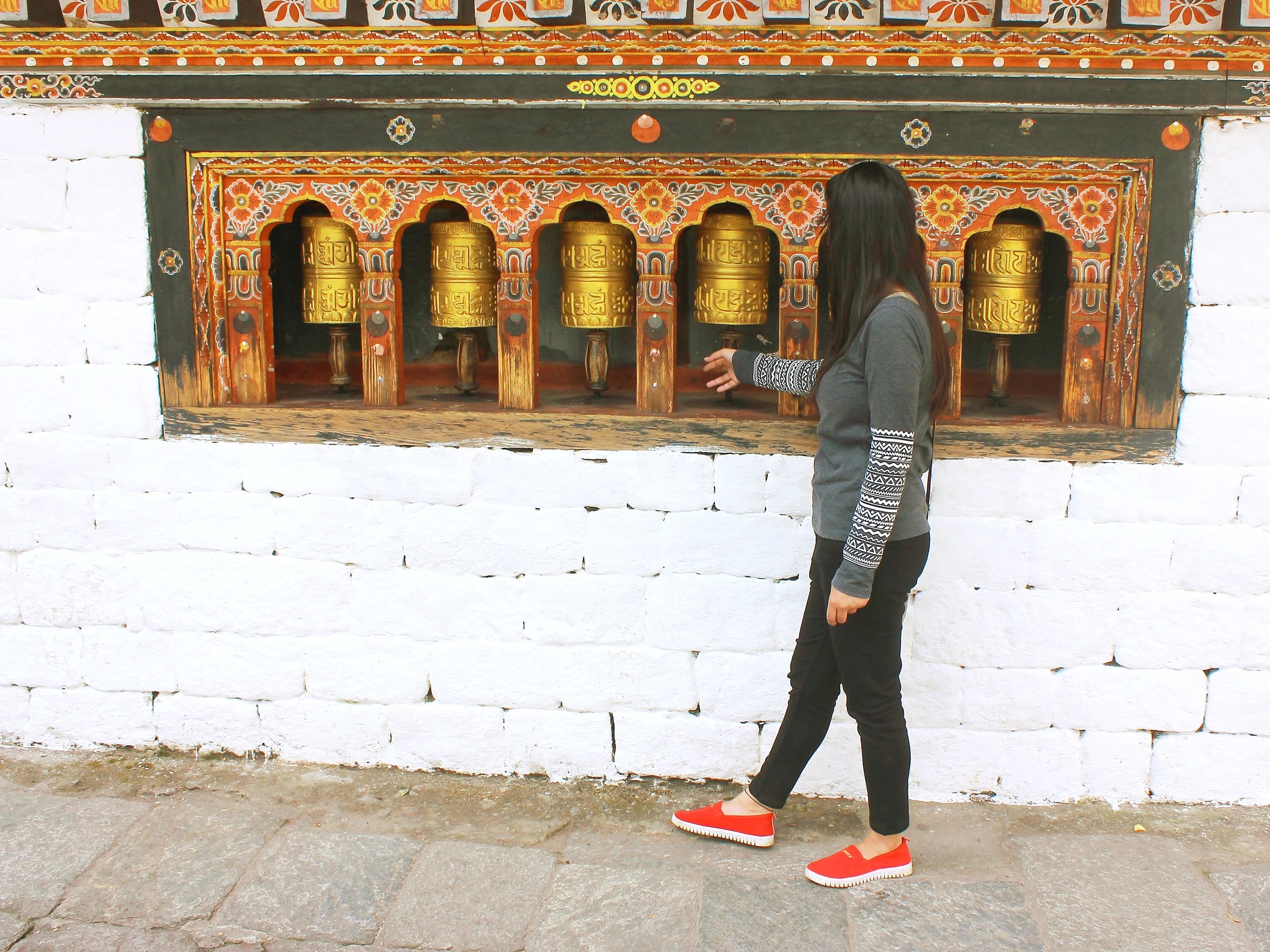 Traveler spinning a Dharma wheel in a monastery in Thimphu